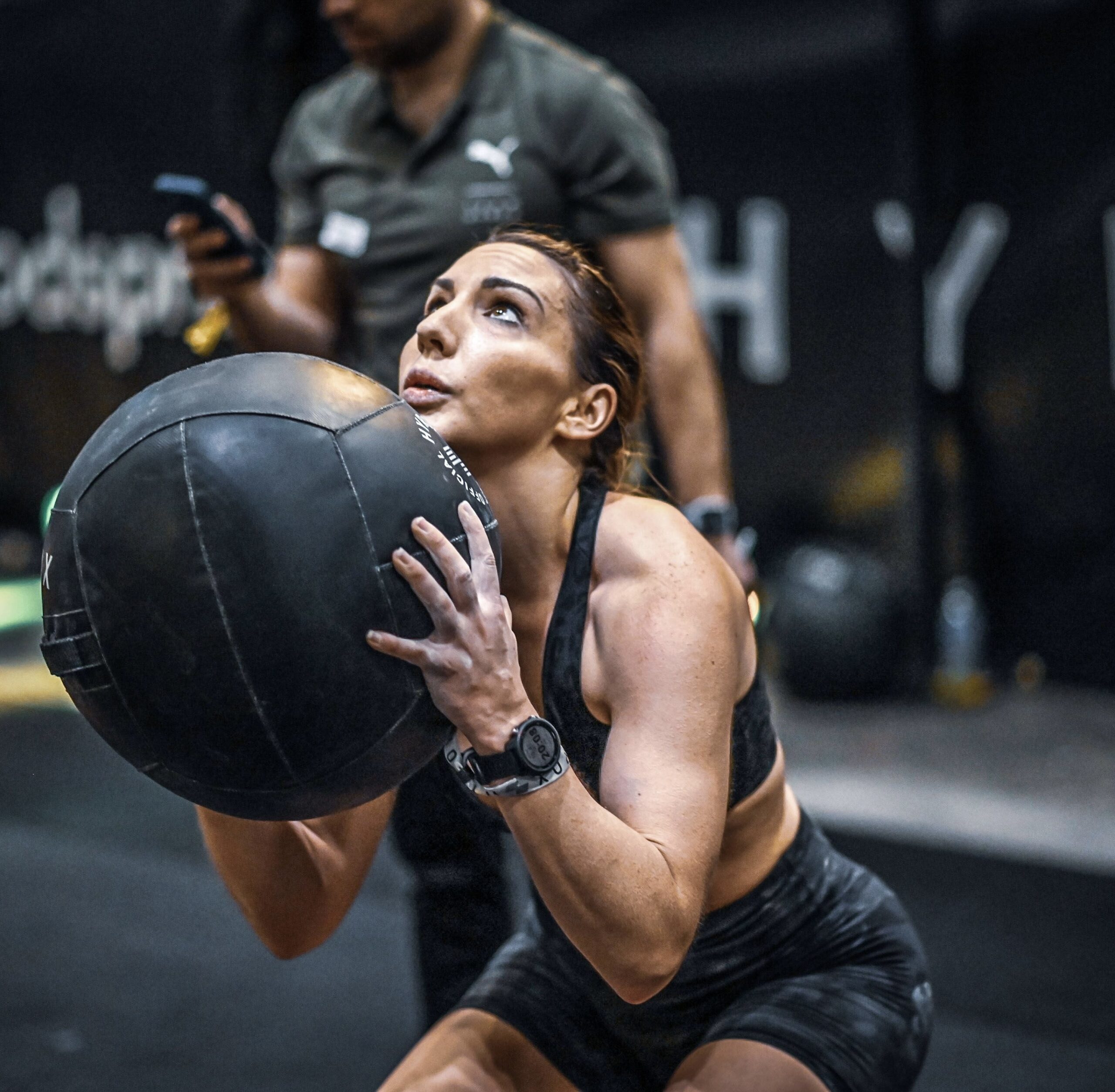 An athlete lifting a medicine ball during a fitness competition
